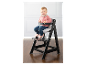 Un jeune enfant assis sur une chaise haute en bois noir.