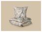 Parure de lit florale avec oreiller et couette pliée sur fond beige.