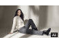 Femme en pull, pantalon gris et bottines noires assise par terre.