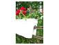 Jardinière blanche avec fleurs rouges et vertes sur une clôture en fer rouillée.