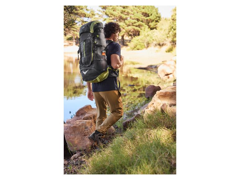 Homme portant un sac à dos Quechua et chaussures de randonnée près d'un lac.