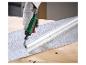 Main gantée utilisant une meuleuse pour travailler un tuyau métallique sur une surface texturée.
