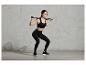 Une femme en vêtements de sport fait des squats avec une barre d'entraînement.