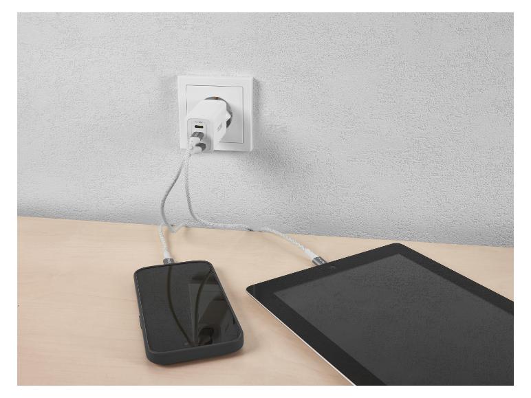 Chargeur secteur PD 45W chargeant téléphone et tablette sur une table en bois.