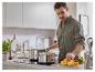 Un homme dans la cuisine, avec deux casseroles sur une plaque à induction et des pâtes fraîches sur une planche à découper.