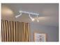 Un luminaire de plafond blanc avec trois spots dirigés vers un mur en bois.