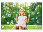 Une fille se balance sur une balançoire avec des bulles de savon autour d'elle.