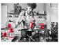 Un homme utilise un mixeur plongeant KitchenAid rouge dans la cuisine.