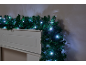 Guirlande de Noël avec lumières LED blanches drapée sur une cheminée blanche.