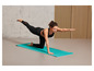 Une femme en vêtements de sport fait du yoga sur un tapis bleu.