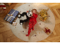 Garçon souriant en pyjama rouge allongé sur un tapis avec des peluches et des cadeaux.