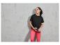 Une femme portant un t-shirt noir et un pantalon rose, tenant une bouteille d'eau.