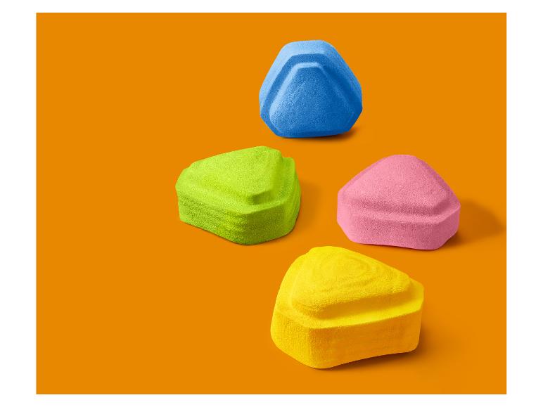 Quatre éponges de maquillage triangulaires colorées sur fond orange.