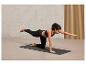 Une femme fait des exercices de yoga sur un tapis noir.