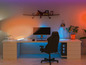 Une chaise de jeu, un ordinateur et un éclairage RGB dans un espace de travail moderne.