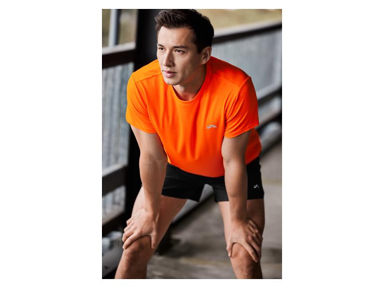 Homme en t-shirt orange et short noir de Jack Wolfskin.
