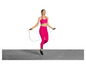 Une femme en tenue de sport rose saute à la corde à sauter.