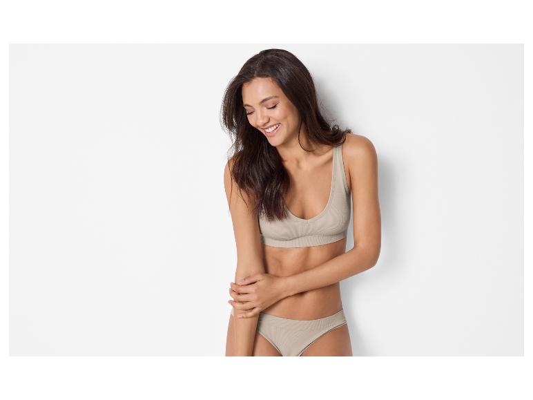 Femme souriante en soutien-gorge et culotte beige.