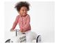Un enfant dans un pull rose conduisant une voiture jouet.