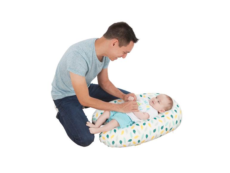 Un père joue joyeusement avec son bébé sur un coussin coloré.