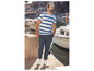 Homme avec un t-shirt rayé, un pantalon bleu et des baskets blanches dans un port.