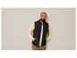 Homme portant un gilet noir et un pull beige.