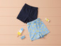 Deux shorts pour enfants, un bleu foncé et un bleu clair avec des soleils jaunes.