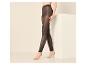 Femme portant des leggings noirs transparents, pieds nus, debout à côté d'un bloc blanc.