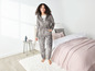 Une femme en pyjama gris à rayures zébrées dans une chambre à coucher.