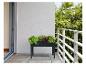 Une jardinière noire avec des plantes vertes sur un balcon