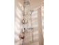 Douche avec pommeau de douche carré, douchette et étagère d'angle avec articles de toilette.