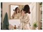 Femme en peignoir se coiffant avec une brosse soufflante devant le miroir de la salle de bain.