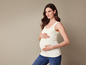 Une femme enceinte portant un débardeur blanc et un jean bleu.