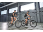 Deux personnes à vélo électrique en intérieur, vêtues de tenues de sport.