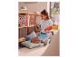 Une fille lit un livre et utilise une tablette, entourée de livres et de fournitures scolaires colorées.