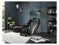 Fauteuil de massage noir dans une pièce moderne avec étagère à livres et plantes.