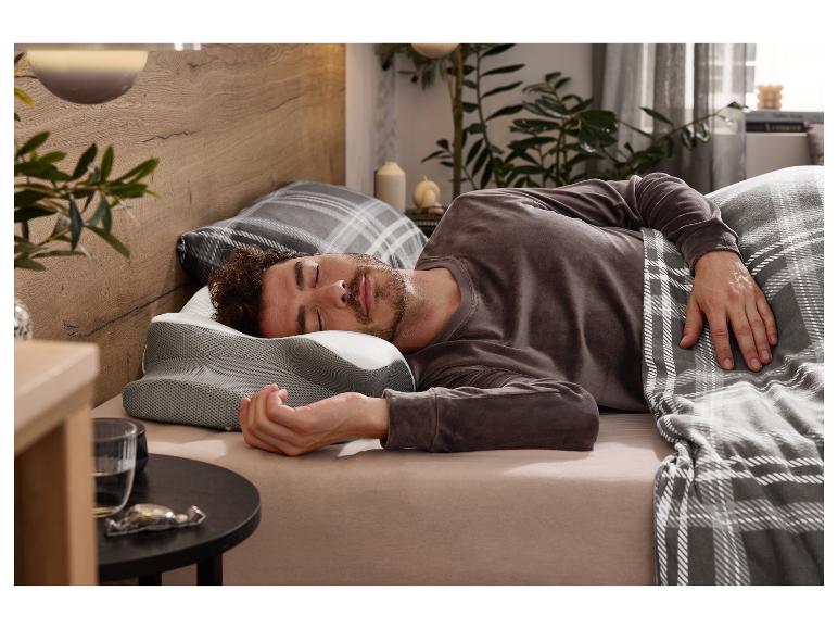 Homme dormant profondément sur un oreiller en mousse à mémoire de forme profilé dans une chambre confortable.