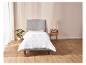Une couette blanche sur un cadre de lit gris dans une chambre à coucher moderne.