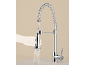 Robinet de cuisine chromé avec douchette extractible et design à ressort, une main tient la douchette qui projette de l'eau.