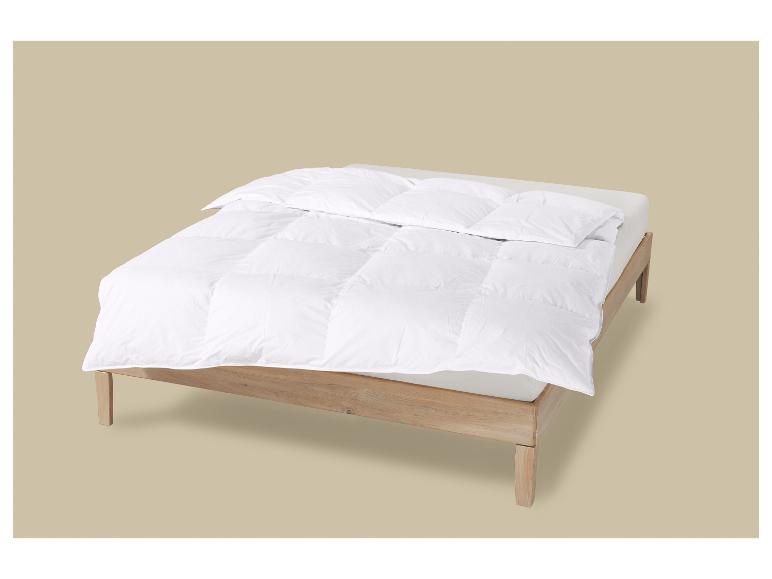 Lit en bois avec couette blanche et oreillers.