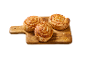 Trois escargots feuilletés au fromage sur une planche à découper en bois.