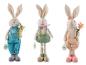 Trois lapins de Pâques en peluche de différentes couleurs avec une carotte, une fleur et une étiquette 'Happy Easter'.