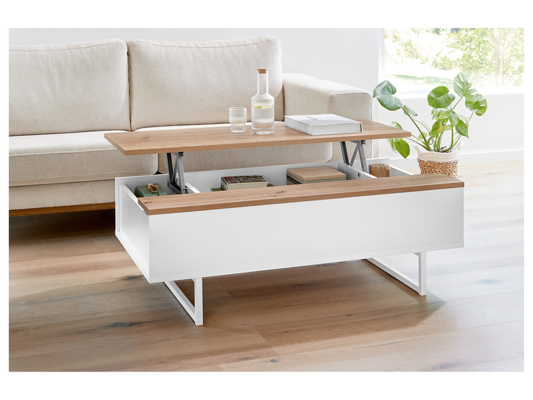 Une table basse blanche avec un plateau relevable et un espace de rangement dans un salon moderne.