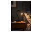 Une lampe de table noire sur une table de chevet à côté d'un lit.