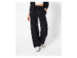 Une femme porte un pantalon noir taille haute et des baskets blanches.
