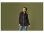 Une femme porte une veste softshell noire avec une fermeture éclair rouge.