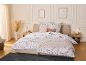 Parure de lit à motif floral dans une chambre chaleureuse avec couverture et oreillers.
