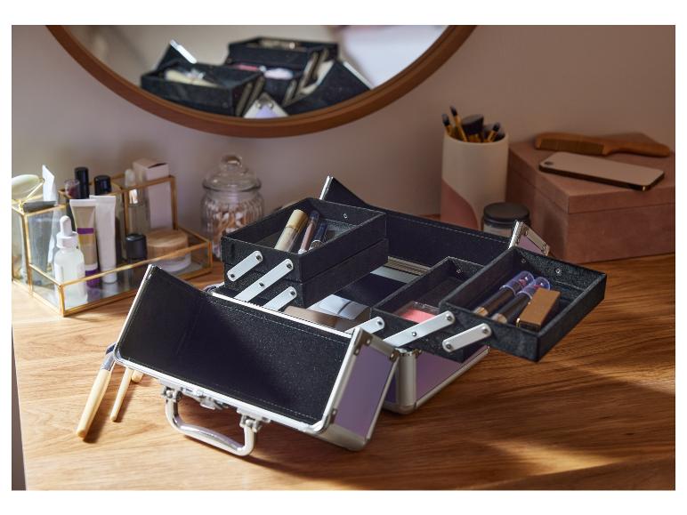 Une trousse de maquillage ouverte avec des rouges à lèvres et des pinceaux de maquillage.