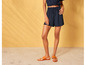 Une femme portant un short bleu et des sandales brunes.