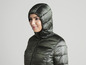 Une femme porte une veste matelassée verte à capuche.